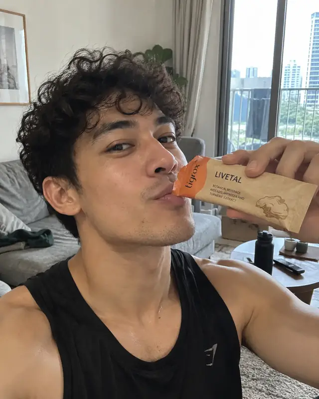 A man drinking a LIVETAL sachet in his living room
