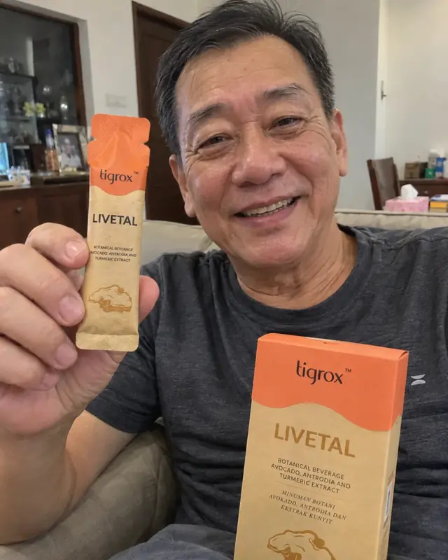 A man smiling on a sofa holding a LIVETAL sachet and box