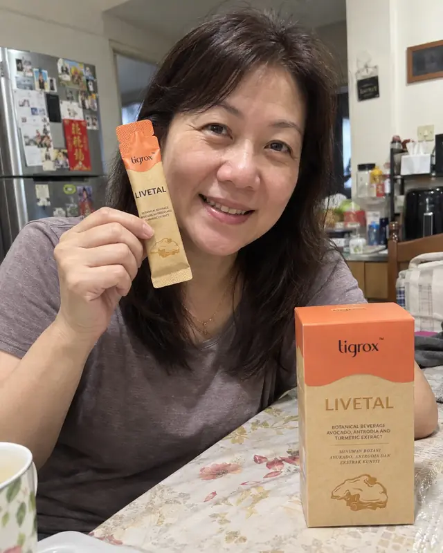 A woman holding a LIVETAL sachet at the dining table with the box beside her