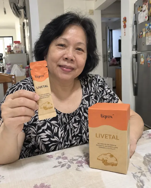 A woman at the dining table holding a LIVETAL sachet with the box in front of her
