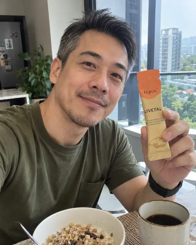 A man holding a LIVETAL sachet at breakfast with a city view behind him