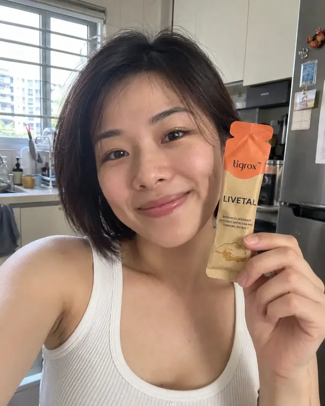 A woman holding a LIVETAL sachet in her kitchen